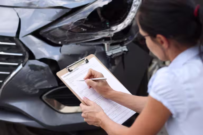 insurance adjuster filling out an auto accident claim form after a car crash